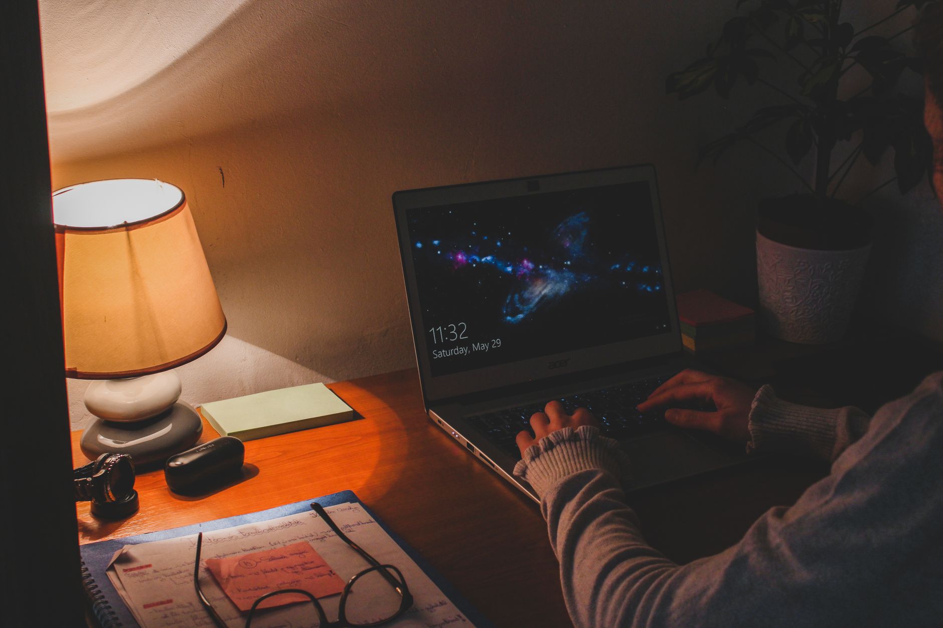 Mãos a digitar num portátil numa mesa com toalha estampada, ambiente doméstico.